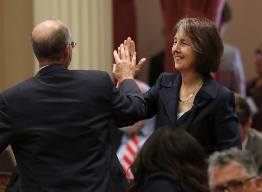 Sen. Nancy Skinner, D-Berkeley, and Sen. Steven Glazer, D-Orinda slap palms in celebration after her measure to let athletes at California colleges hire agents and sign endorsement deals was approved by the Senate in Sacramento, Calif., Wednesday, Sept. 11, 2019. The bill now goes to Gov. Gavin Newsom, who has not said whether he will sign it. (AP Photo/Rich Pedroncelli)