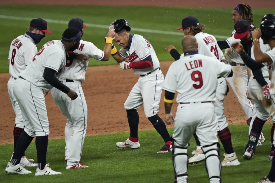 Cleveland Indians Cesar Hernandez, center, is mobbed by teammates after hitting an RBI-single in the ninth inning in a baseball game against the Milwaukee Brewers, Saturday, Sept. 5, 2020, in Cleveland. (AP Photo/Tony Dejak)
