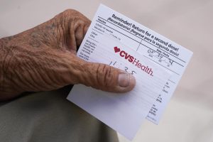 In this May 3, 2021 file photo, a man holds his vaccination reminder card after having received his first shot at a pop-up vaccination site. 