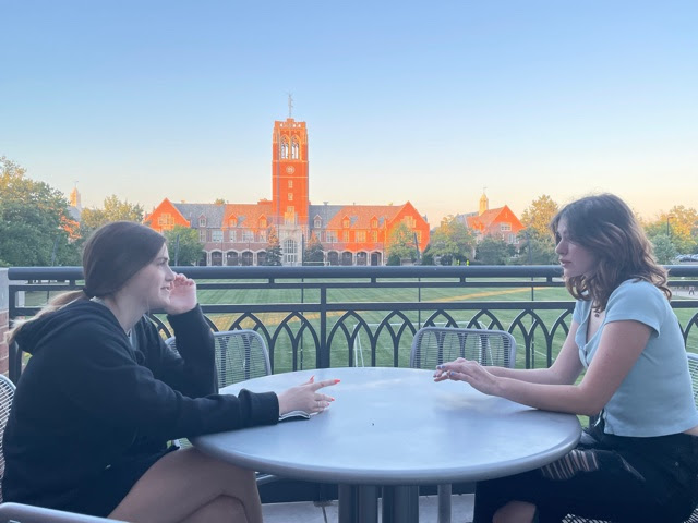 Caroline Padden 25 and Clare Atheneos 25 share a conversation on the balcony of Dolan Science Center.