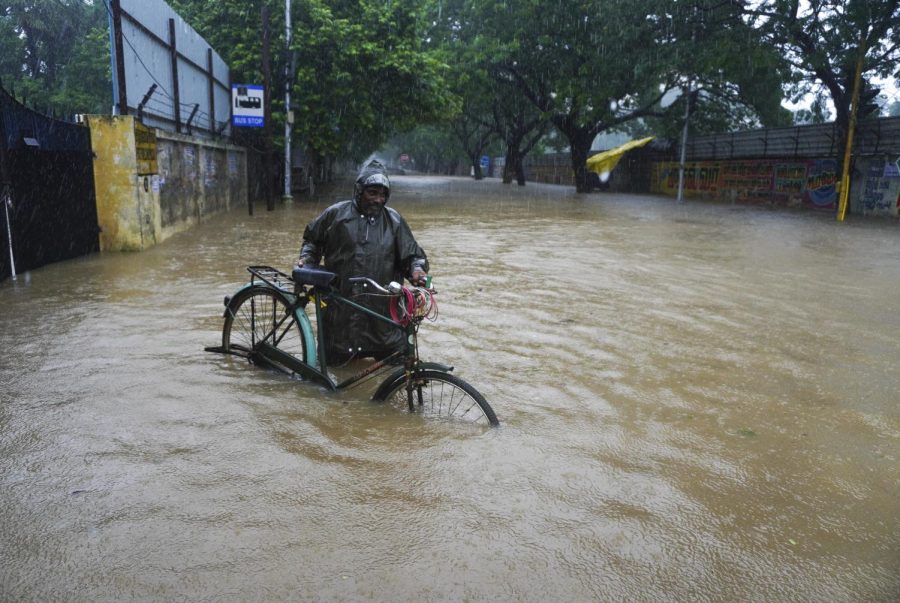 A man pushes his cycle past a flooded street in Chennai, in the southern Indian state of Tamil Nadu, Thursday, Nov. 11, 2021.