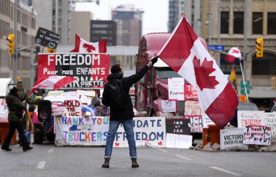 A protester waves a Canadian flag in front of parked vehicles on Rideau Street at a protest against COVID-19 measures that has grown into a broader anti-government protest, in Ottawa, Ontario, Friday, Feb. 11, 2022.