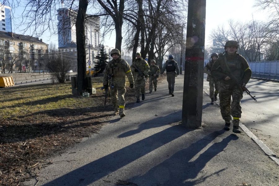 Ukrainian soldiers patrol an area not far from burning military trucks in a street in Kyiv, Ukraine, Saturday, Feb. 26, 2022. Russian troops stormed toward Ukraines capital Saturday, and street fighting broke out as city officials urged residents to take shelter. 