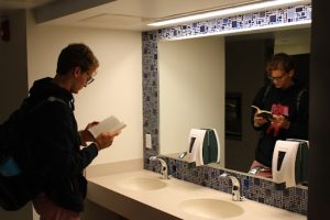 Fogle, RA of the special programs (which includes the Honors Program, of which Fogle is a member) floor in Dolan Hall, gets in some light reading as he waits for his hands to dry after washing them with warm water and soap for 60 second -- as recommended by the CDC.
