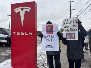 Protestors pose in front of Tesla sign at Lyndhust-Cleveland Service Center