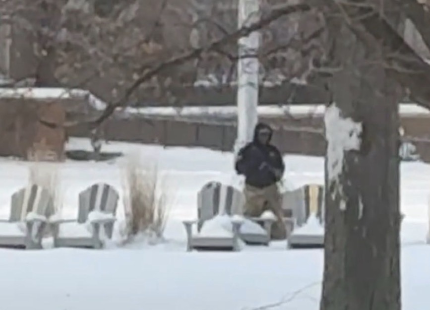 Man seen on campus standing motionless while staring at students with a rifle.